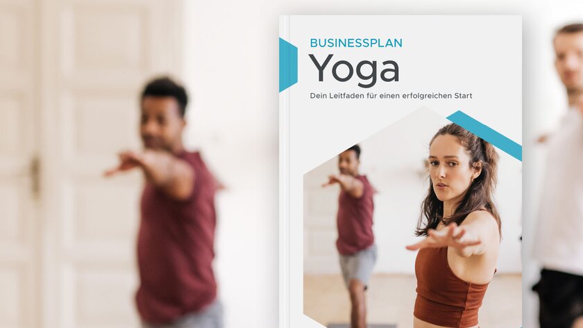 Yogalehrerin in Warrior-II-Pose trägt Sportleggings und fokussiert entschlossen die Kamera, zwei Männer im Hintergrund folgen ihrem Beispiel.