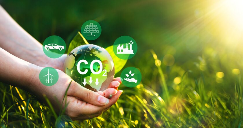 Zwei Hände halten symbolischen Erdball mit Aufforderung zur Reduktion von CO2 durch nachhaltige Entwicklung auf der Grundlage erneuerbarer Energien.