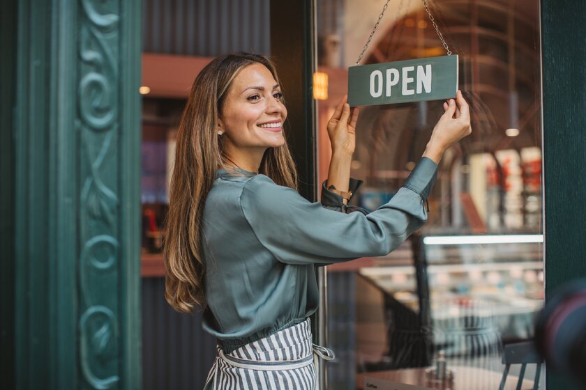 Happy small business owner opens her store.