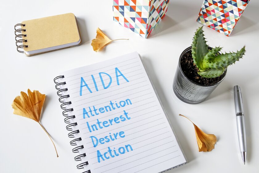 AIDA Aufmerksamkeit Interesse Wunsch Aktion in einem Notizbuch geschrieben