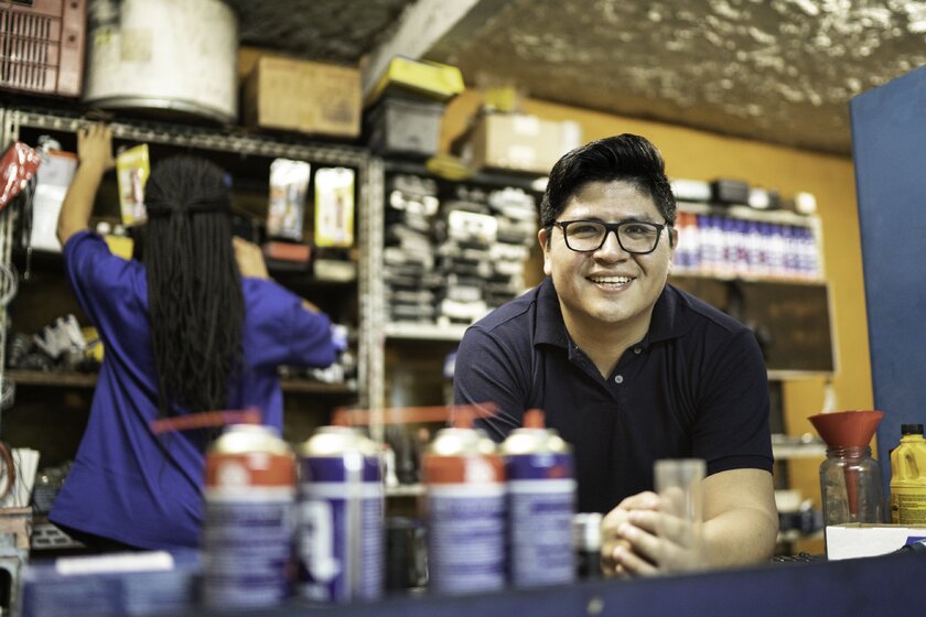 Portrait of a smiling Mexican-born mechanic working in his car repair shop.