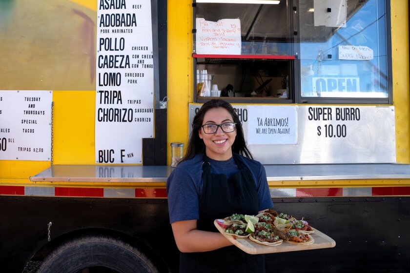 Young mexican entrepreneur in front of her food truck.