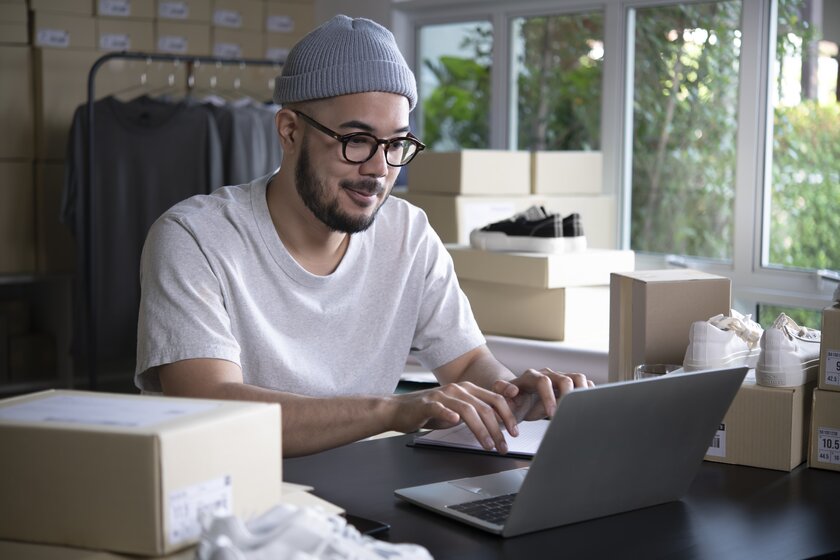  Happy male online seller taking note of orders from customers.