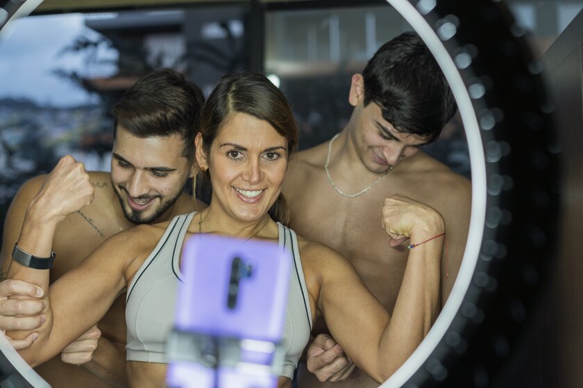 Familienunternehmen aus Mutter mit ihren beiden Söhnen zeigt Muskeln und hat Spass beim Dreh von Fitness-Video für TikTok.