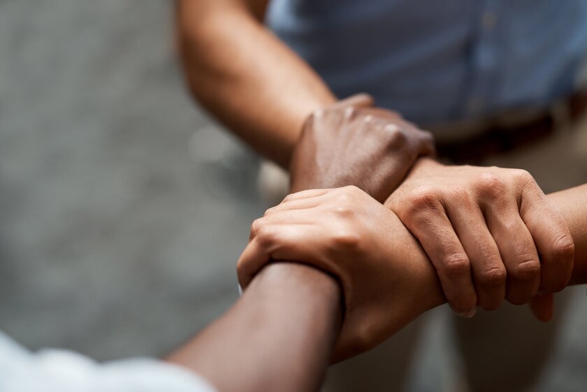 Three people holding each other by their wrists forming a strong network.