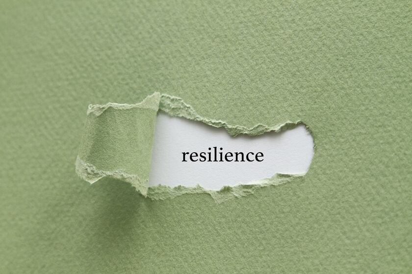 Abgerissenes Papier an einer Wandfläche enthüllt den Begriff der Widerstandsfähigkeit oder Resilienz.