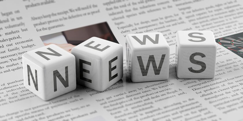 Individual cubes lying on a newspaper with the word News written on them.
