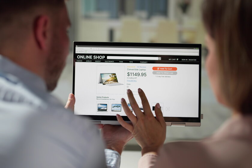 Blick von hinten auf Silhouetten eines Mannes und einer Frau beim heimischen Onlinekauf.