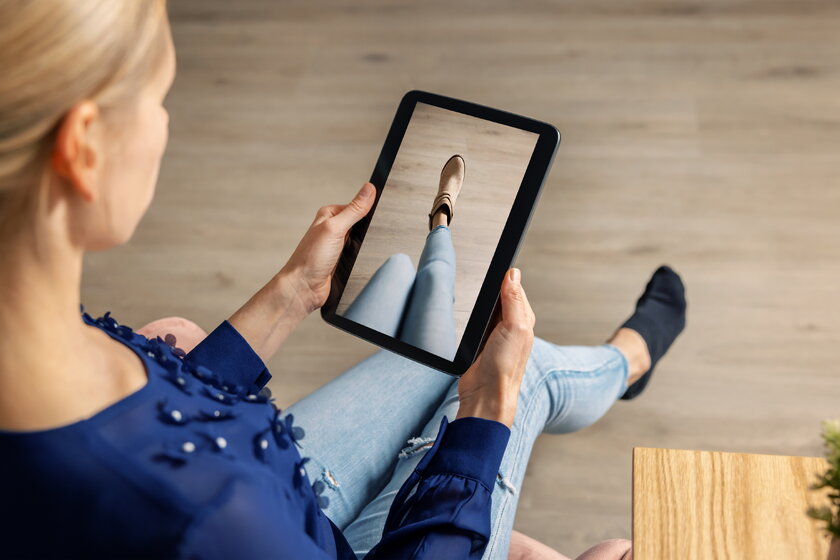 Bild einer Frau, die Schuhe online mit digitalem Tablet anprobiert.