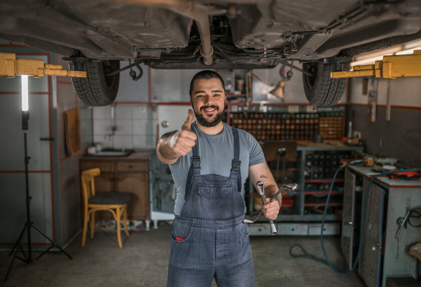 Image of a car mechanic in his workshop with thumbs up.