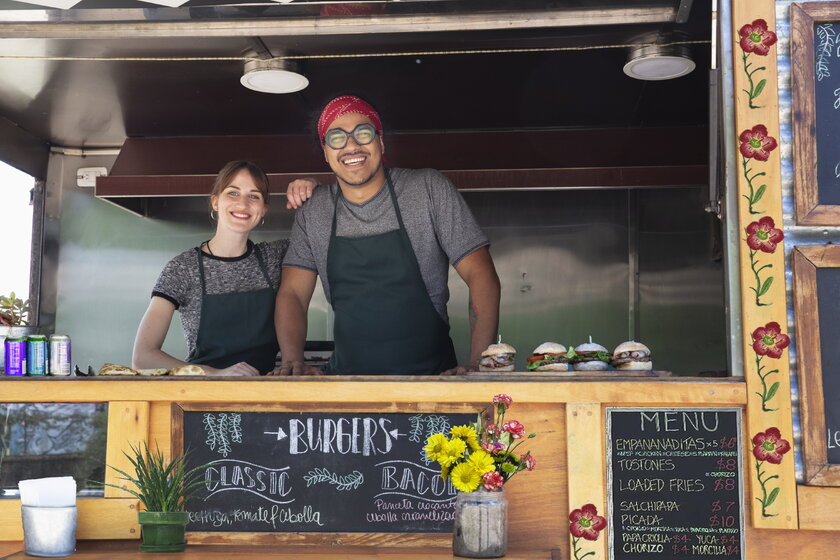 A couple of small business entrepreneurs, a man and a woman stand at the counter of their food truck.