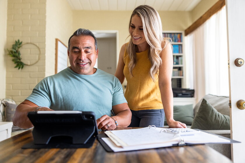 A man and a woman process their tax return on their home laptop.