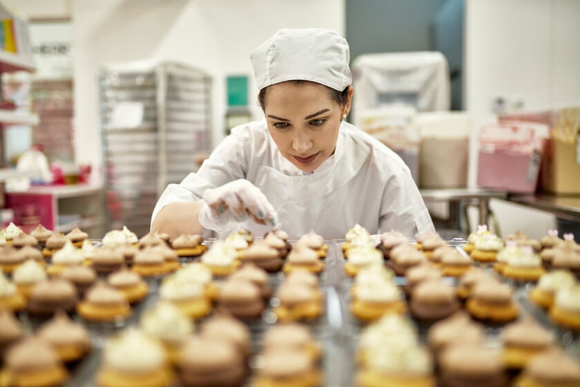 A pastry chef sorts small cupcakes in her bakehouse.