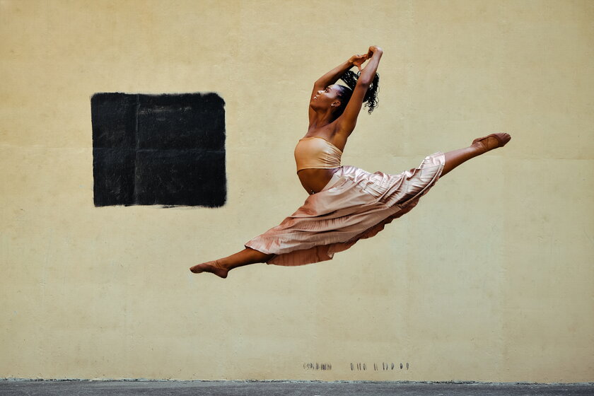 Modern ballerina dancer jumps in the air with wide open legs.