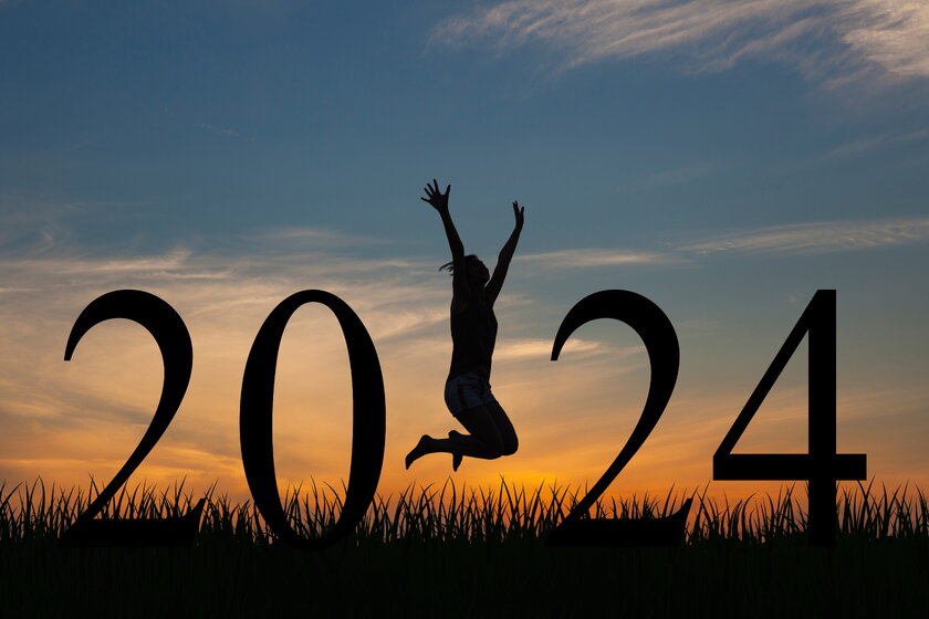 Woman in the twilight jumps between large letters into "2024".