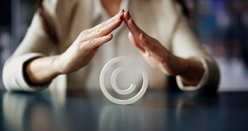 Bild Copyright Zwei Haende einer Frau formen schuetzendes Dach ueber Copyright-Symbol.