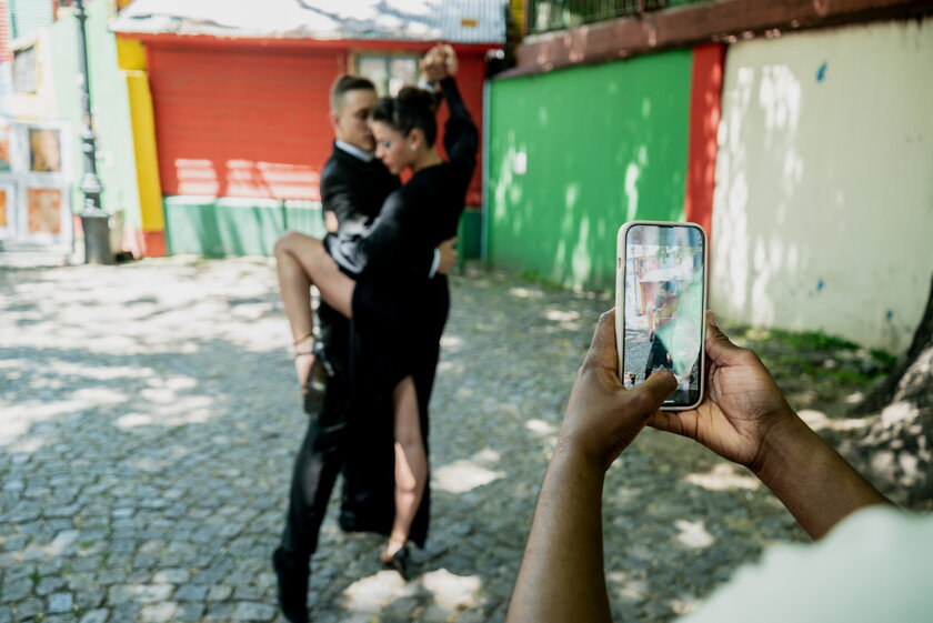 Mann und Frau tanzen Tango auf der Strasse und werden mit Smartphone gefilmt.