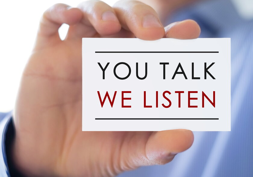 Man holds business card up to camera: You Talk. We Listen.