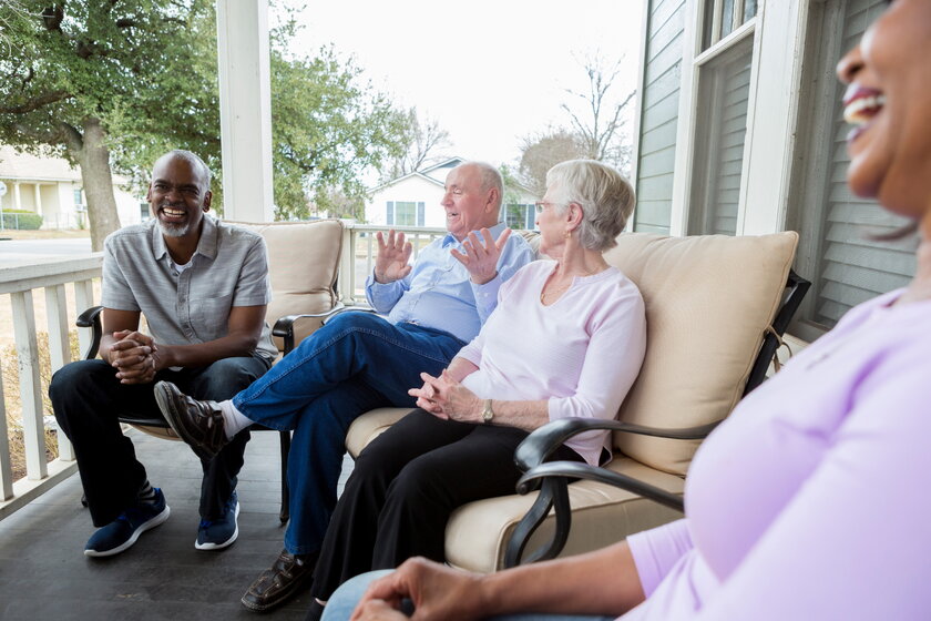 Group of neighbors sitting on a porch enjoying each other's company.